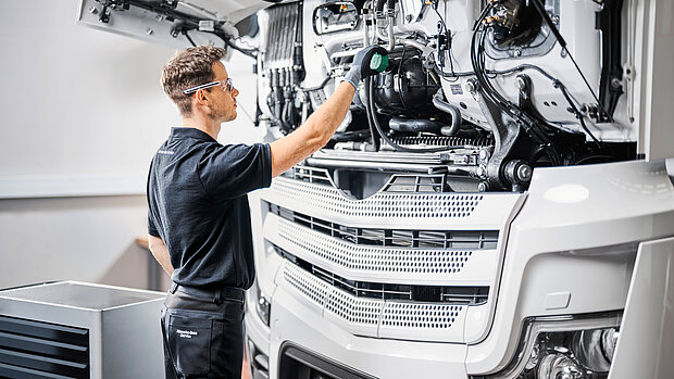 Mitarbeiter vor geöffneter Motorhaube eines weißen Lkws