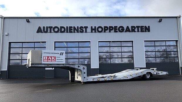 Spezialtieflader 1-Achs-Sattelauflieger Tiefbett vor Werkstatttor